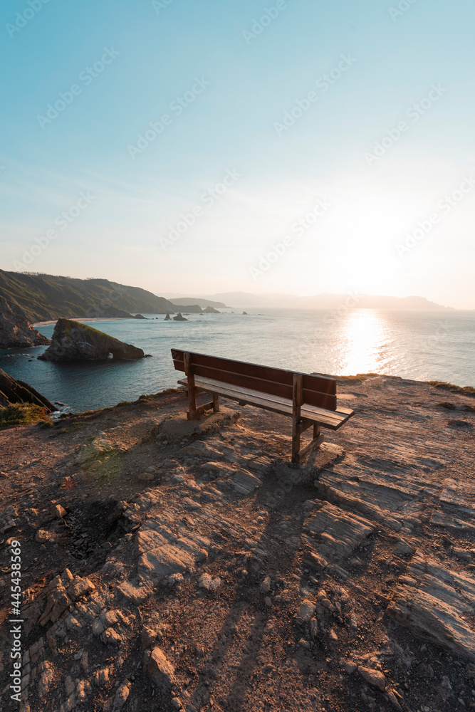 Empty bench standing at edge of coastal cliff at sunset Empty bench standing at edge of coastal cliff at sunset