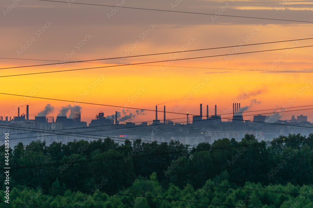 Smoking chimneys at dawn. Forest, industrial landscape and wires. The border of nature and civilization.