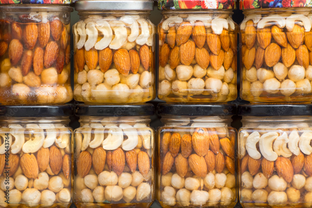 Hazelnuts, cashew and almond canned with honey in glass jars. Harvest of nuts. Homemade preservation in autumn.