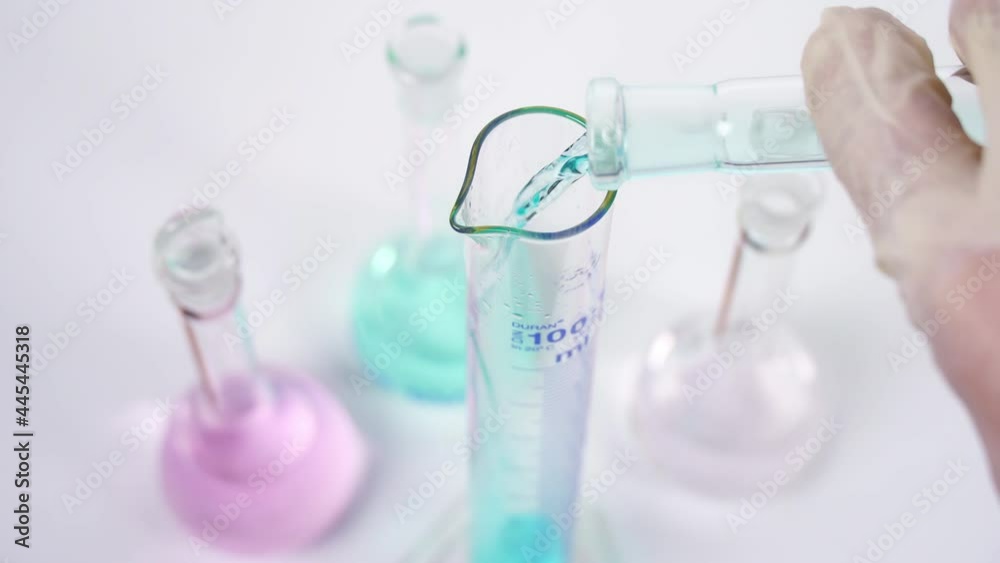 Scientists pour blue chemical liquid into beaker in laboratory. Scientists pour blue chemical liquid into beaker in laboratory.