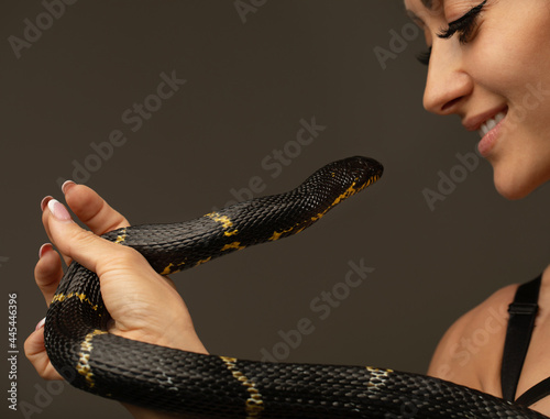 Sexy woman with a snake on grey background.