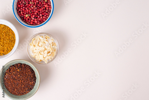 Colourful set different spices for meat, vegetarian dishes in bowls on light background. Seasoning pink peppercorns, dried onions, sun dried tomatoes, curry. Hot spicy for cooking, copy space