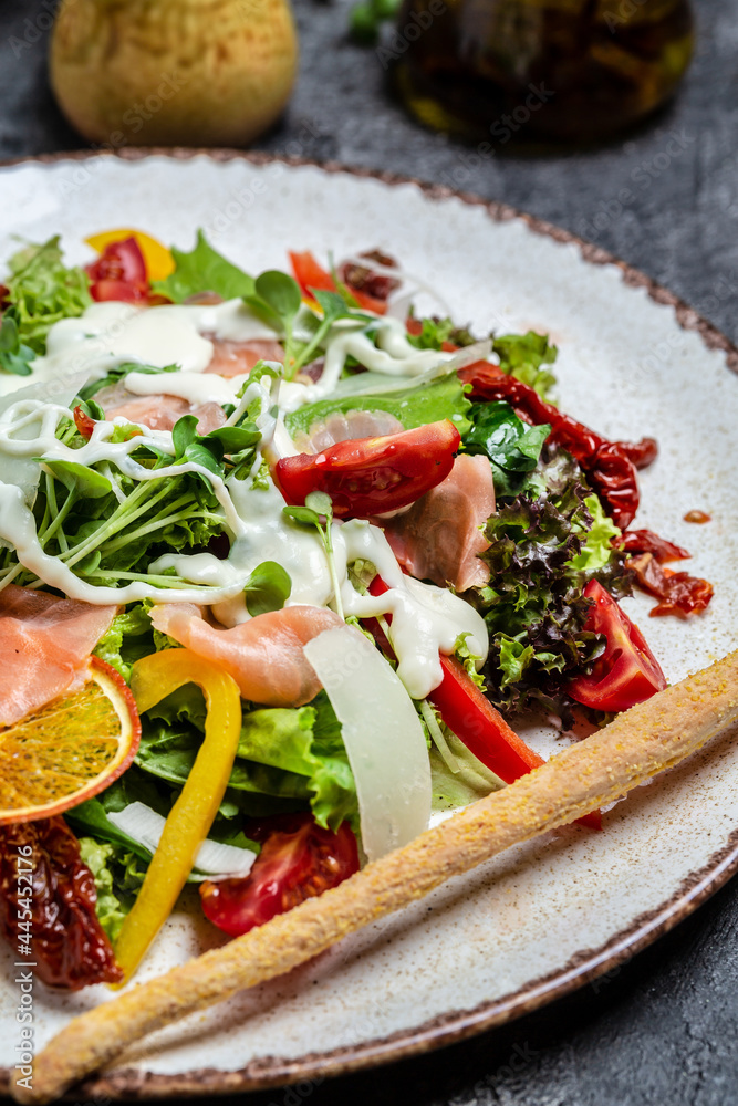salad with Smoked salmon, lettuce, sun-dried tomatoes and cheese sauce, vertical image. top view salad with Smoked salmon, lettuce, sun-dried tomatoes and cheese sauce, vertical image. top view