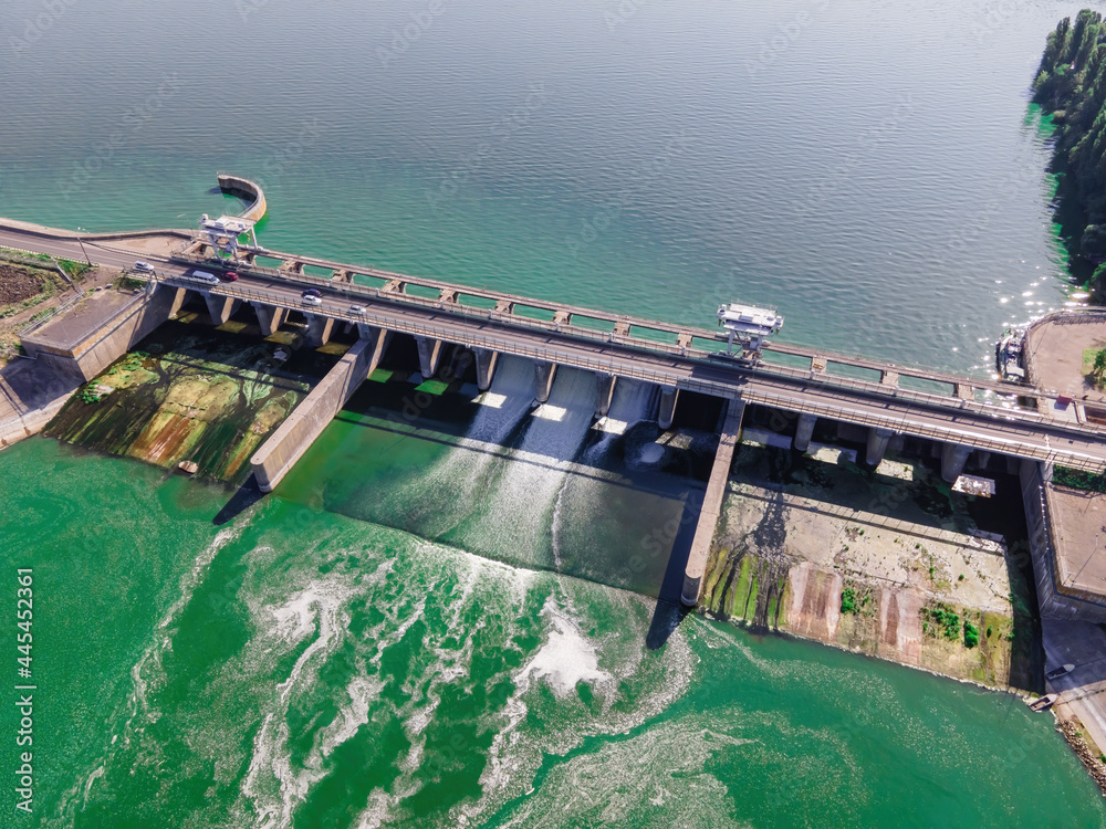 Hydroelectric dam with flowing green water through gate, aerial view from drone