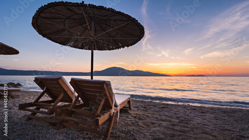 Fotografering Romantic sunset on the beach with two deck chair under umbrella