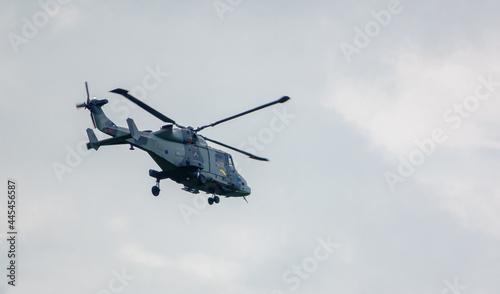 helicopter flying low in a cloudy blue grey and white summer sky