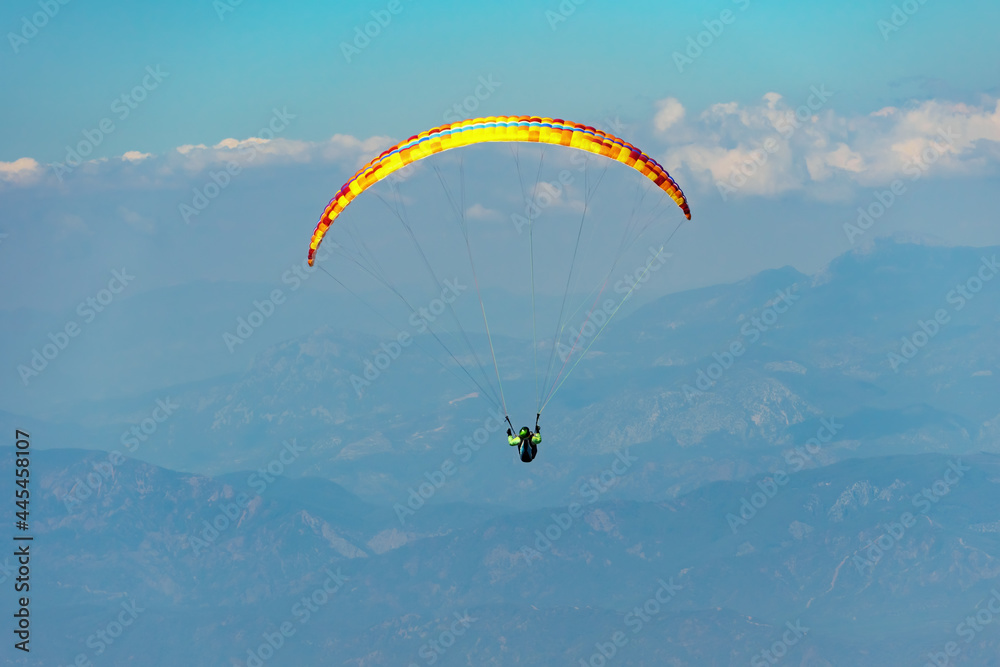 Paraglider soaring on paragliding in the sky in mountain. Extreme sport in mountains Paraglider soaring on paragliding in the sky in mountain. Extreme sport in mountains