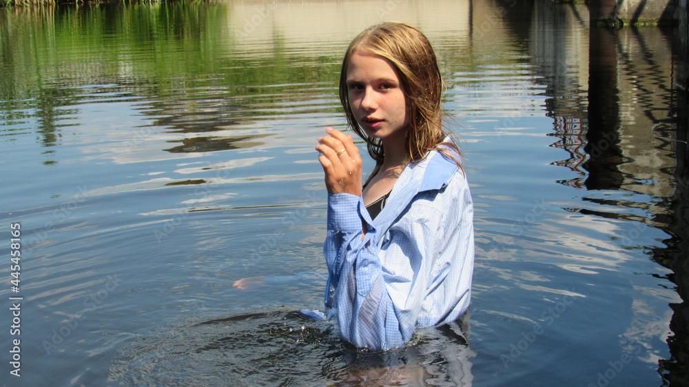 A young and beautiful girl in a shirt posing in the water