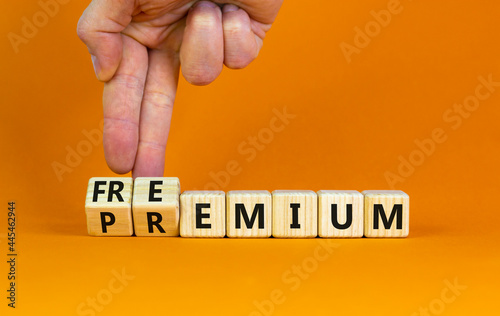Premium or freemium symbol. Businessman turns wooden cubes and changes the word 'premium' to 'freemium'. Beautiful orange background. Business, premium or freemium concept. Copy space. photo