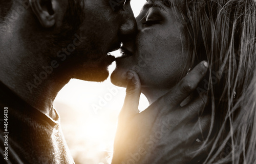 Couple in love kissing on sunset - Boyfriend and girlfriend hugging outdoor - Two lovers having romantic date - Black and white filter - Love background concept photo