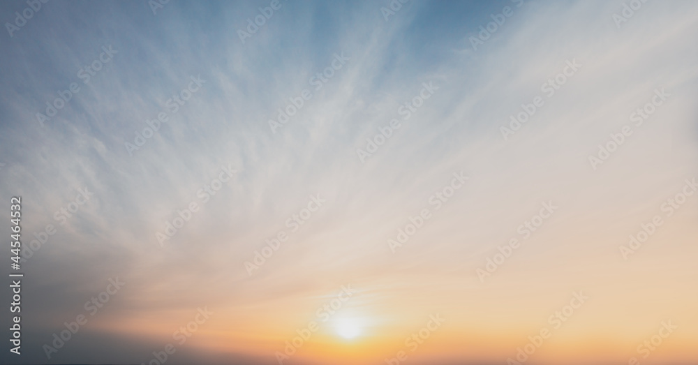 Sunset sky with yellow sun in warm clear weather on a summer evening. Cirdle clouds at sunset - heavenly background in clear weather.
