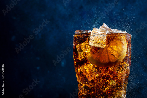 Cold cola with lemon and ice on blue background