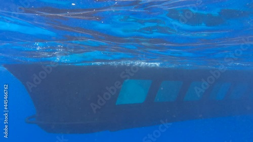 Aquascope submarine with tourists on board swim near coral reef in the blue water. Yellow submarine floats in blue water, people look at the underwater world through portholes  photo