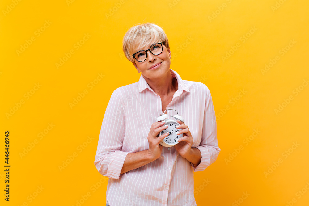 Dreamy Lady in pink shirt holds alarm clock Dreamy Lady in pink shirt holds alarm clock