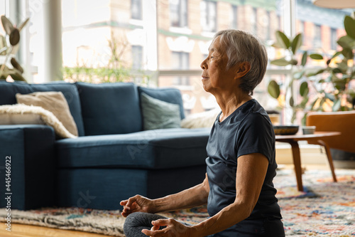 Asian senior woman meditating and relaxing at home in living room
