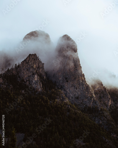 Mountain peaks emerging from fog on sunny afternoon photo