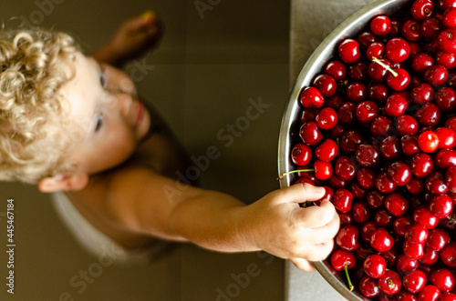 boy 2 years old reaching for a cherry, top view