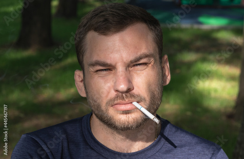 Middle-aged adult man with cigarette in the mouth looking in camera.