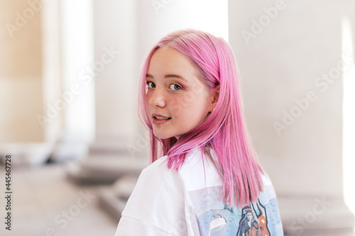 Portrait of a positive pink-haired teenage girl in a white T-shirt.Street style.Summer concept.Generation Z style.Copy space for text. photo