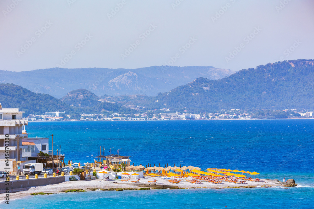 Colorful umbrellas and sunbeds on an empty beach resort - vacation concept on Greece islands in Aegean and Mediterranean seas Colorful umbrellas and sunbeds on an empty beach resort - vacation concept on Greece islands in Aegean and Mediterranean seas