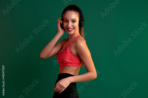 Young smiling sportive girl listening to music on headphones after playing sports exercise © khmelev