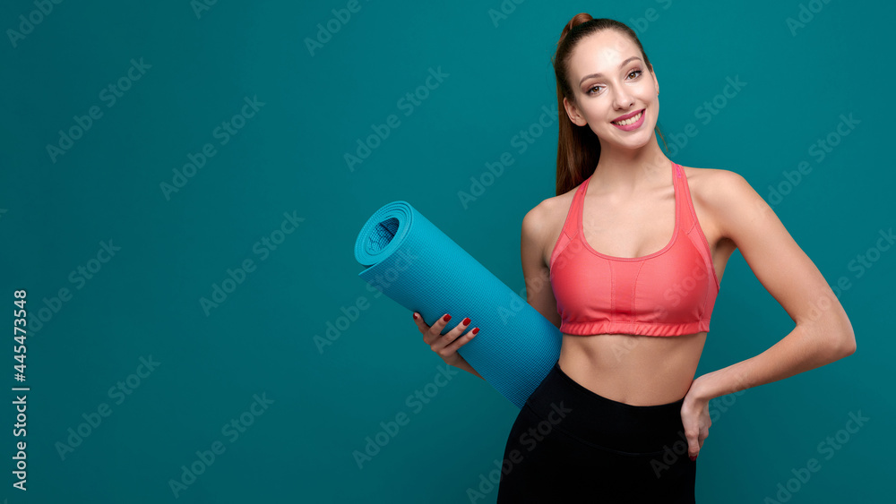 Young sporty smiling woman in sportswear holding yoga mat in her hands Young sporty smiling woman in sportswear holding yoga mat in her hands