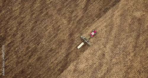 Aerial view of a tractor pulling a plow and an anhydrous tank of ammonia in a farmer's field. Heavy machinery during cultivation, work in the fields. Agricultural tractor in the field.
