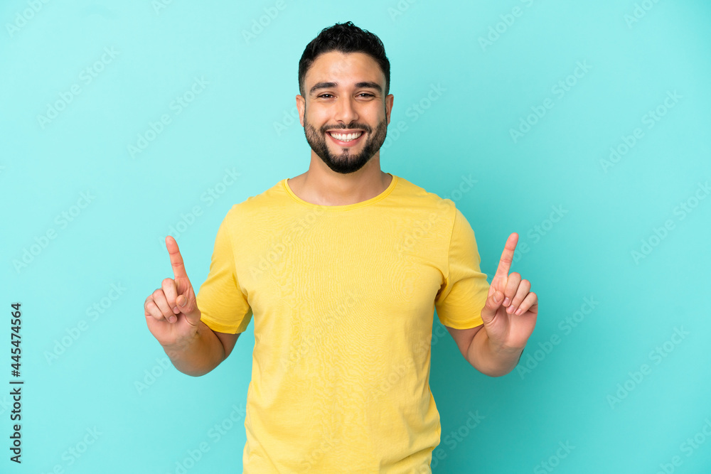 Young arab man isolated on blue background pointing up a great idea