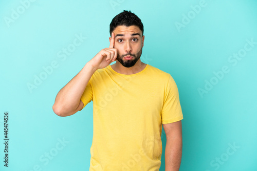 Young arab man isolated on blue background thinking an idea