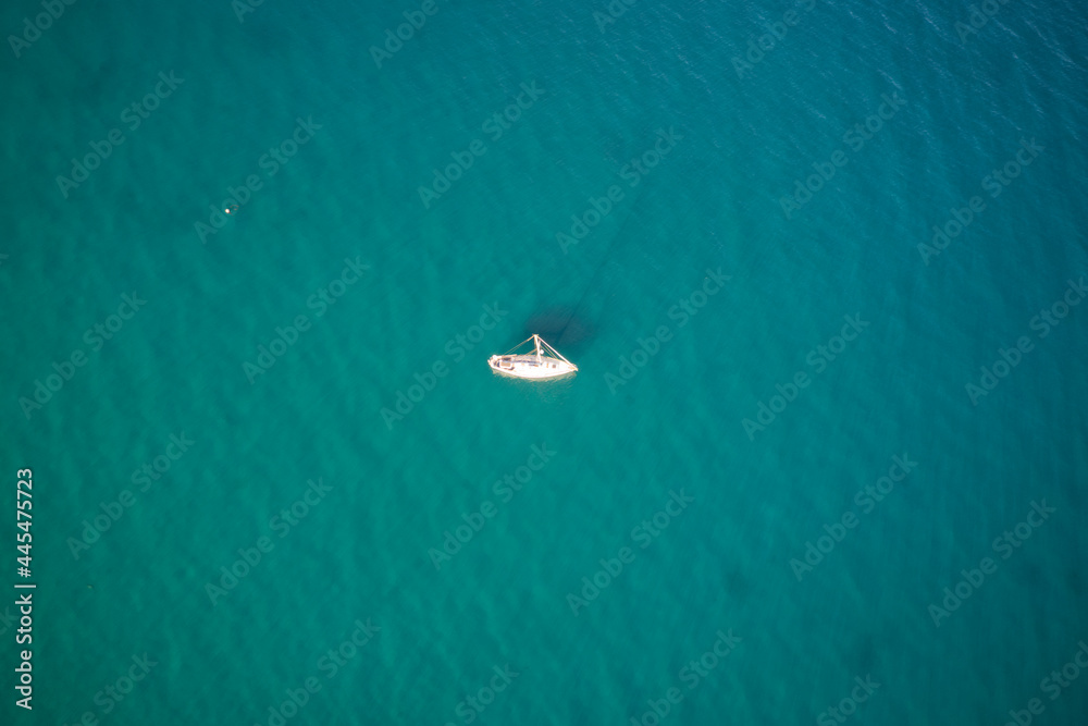 A high definition aerial view of a sailboat in the ocean.