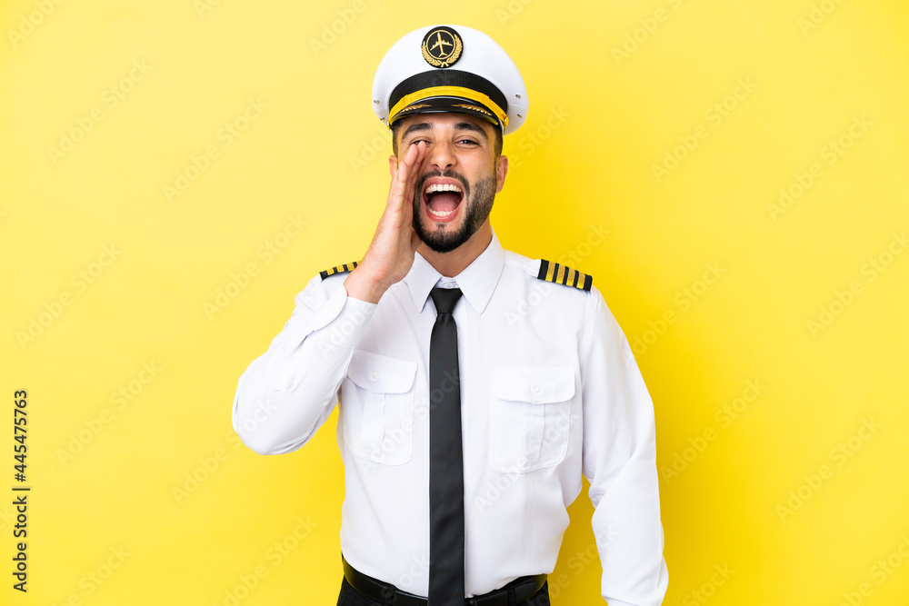 Airplane arab pilot man isolated on yellow background shouting with mouth wide open Airplane arab pilot man isolated on yellow background shouting with mouth wide open