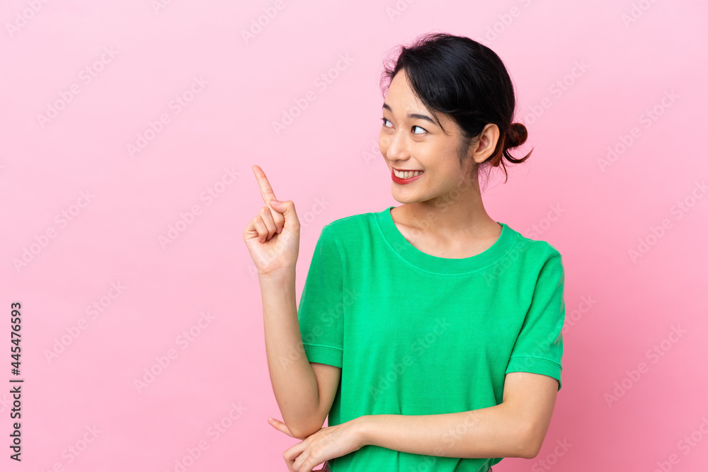 Young Vietnamese woman isolated on pink background pointing up a great idea Young Vietnamese woman isolated on pink background pointing up a great idea