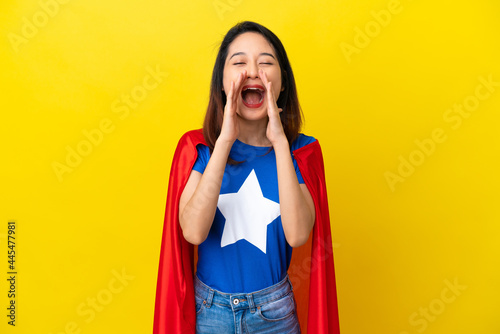 Super hero Vietnamese woman isolated on yellow background shouting and announcing something