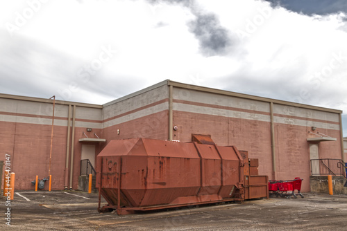 A large trash and waste compactor behind a building