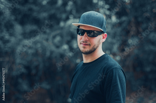 white man in cap, sunglasses and black t-shirt on neutral background