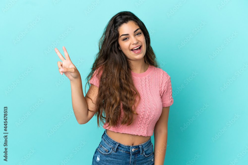 Young caucasian woman isolated on blue background smiling and showing victory sign Young caucasian woman isolated on blue background smiling and showing victory sign