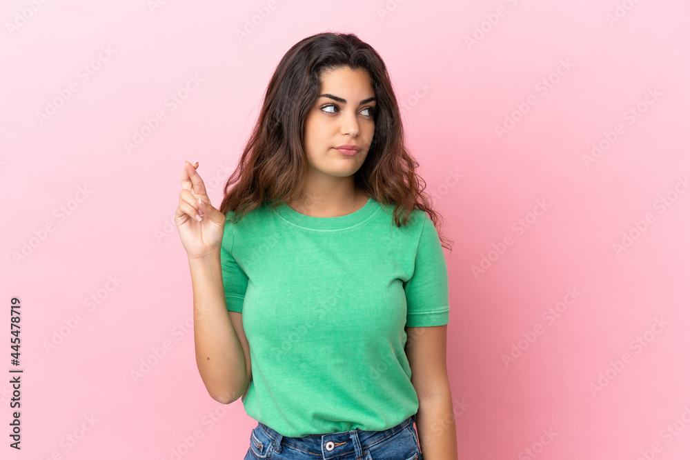 Young caucasian woman isolated on pink background with fingers crossing and wishing the best