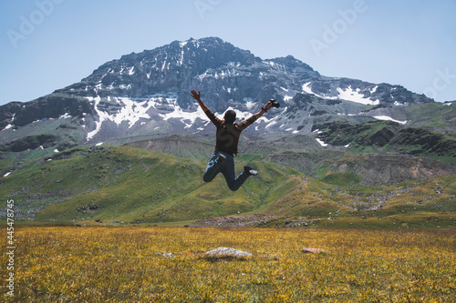 The hiker jump after climbing.  Beautiful  alpine clear lake and mountains. Volcano mountain Aragats Armenia