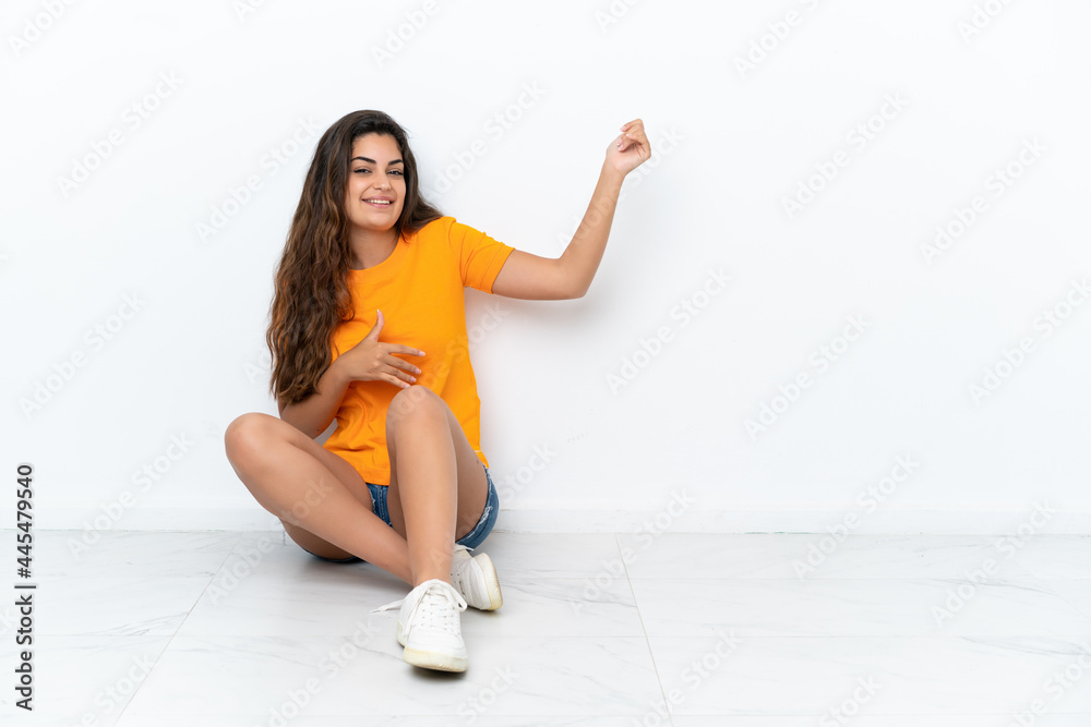 Young caucasian woman sitting on the floor isolated on white background making guitar gesture Young caucasian woman sitting on the floor isolated on white background making guitar gesture
