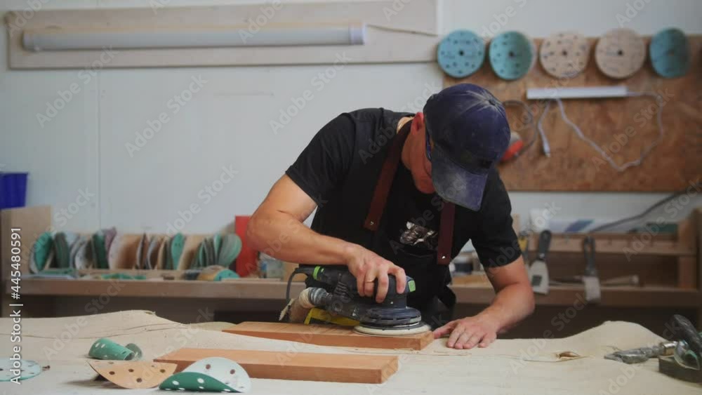 Carpentry works - man worker grinding the surface of a wooden detail Carpentry works - man worker grinding the surface of a wooden detail