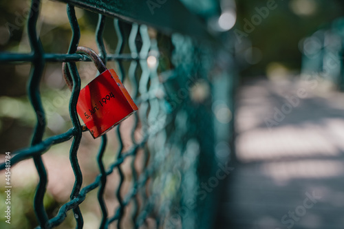 Closeup shot of a red padlock with the number 1994 on a metal fence