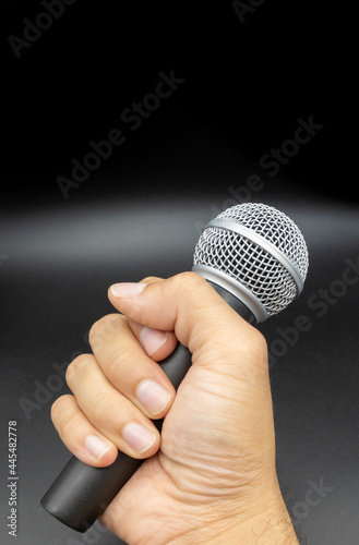 man hand holding microphone on black background, sing concept