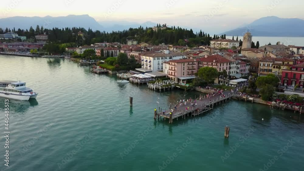 Cinematic 4K aerial drone shot of an arriving boat at the old town of Sirmione, a popular tourist destination with a castle, old churches and a roman villa on the shores of Lake Garda in Italy Cinematic 4K aerial drone shot of an arriving boat at the old town of Sirmione, a popular tourist destination with a castle, old churches and a roman villa on the shores of Lake Garda in Italy