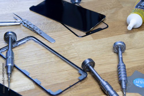 Bangkok, Thailand - 29 May 2021: Close-up shot of the broken screen of the iPhone 11 with tools waiting for repair on a wooden floor. photo