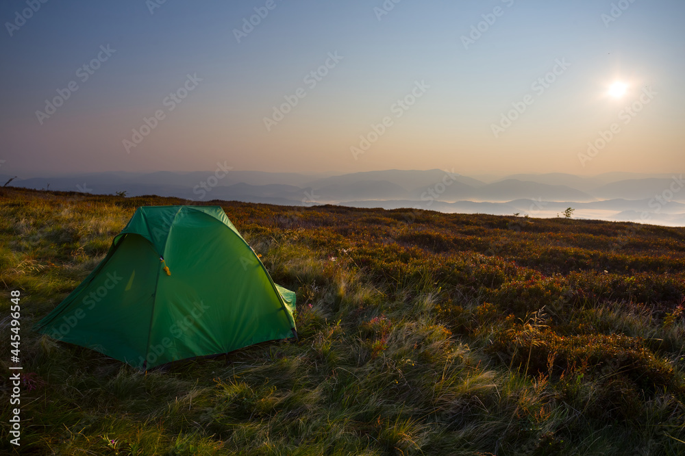 small green touristic tent stay on mount  slope at the early morning, natural travel scene