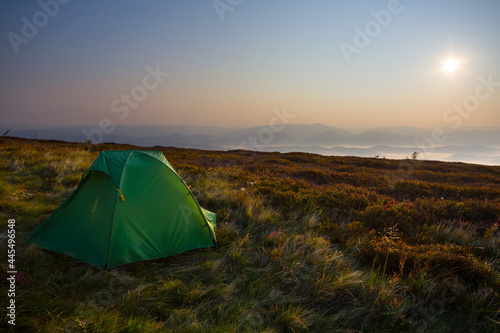 small green touristic tent stay on mount  slope at the early morning  natural travel scene