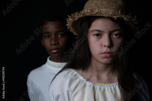 white and Dark skinned kids looking at camera on black background, different ethnicity concept, Caucasian, African, selective focus