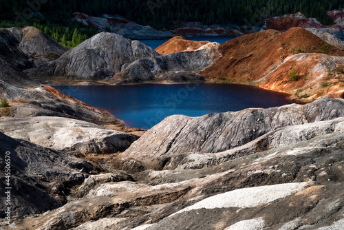 Landscape like a planet Mars surface. Ural refractory clay quarries. Nature of Ural mountains, Russia. The hardened red-brown surface of the earth. Blue lake