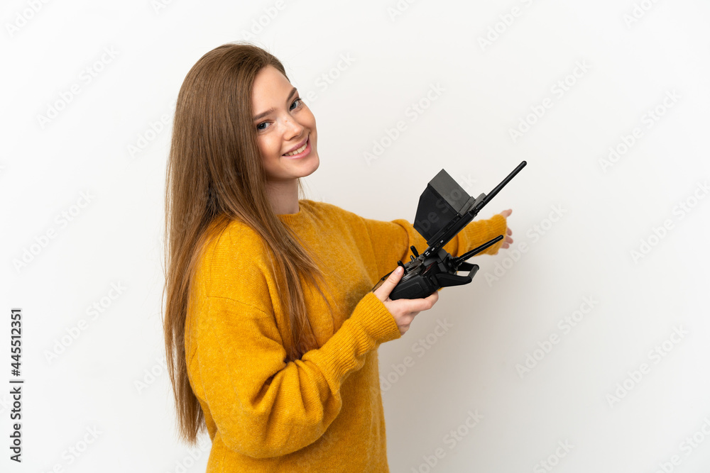 Teenager girl holding a drone remote control over isolated white background extending hands to the side for inviting to come Teenager girl holding a drone remote control over isolated white background extending hands to the side for inviting to come