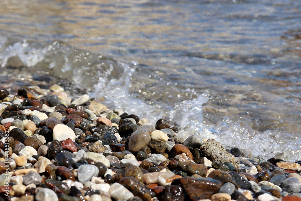 Wet pebble stones on blurred background of sea waves. Summer beach, vacation concept Wet pebble stones on blurred background of sea waves. Summer beach, vacation concept